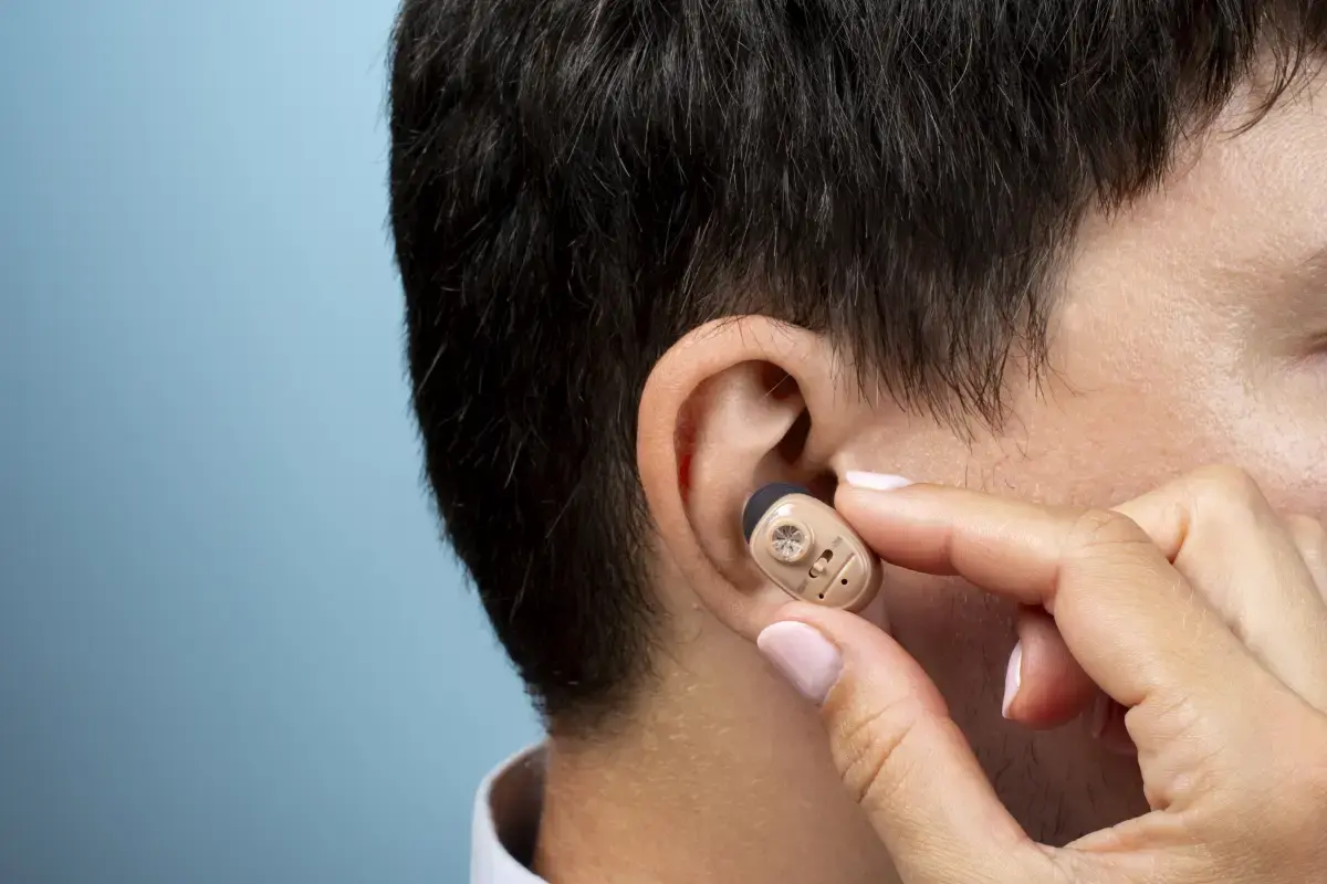 Close-up of a person inserting an in-canal hearing aid